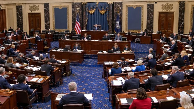 A formal session of the U.S. Senate is underway in the ornate chamber, with members seated at their desks and officials presiding from the front dais beneath the American flag. The image illustrates the legislative setting where the CLARITY Act, which seeks to define regulatory jurisdiction over digital assets between the SEC and CFTC, remains pending after failing to advance on September 15, 2026.