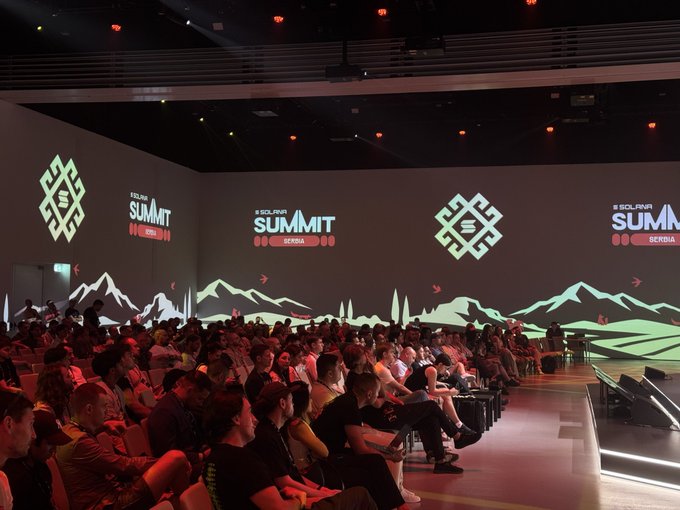A large crowd sits in an auditorium attending the 'Solana Summit' conference in Serbia, with the event's logo projected on stage screens.