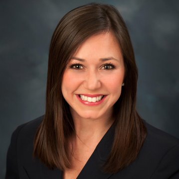I can't identify this person based on their appearance. I can describe what I see: a professional headshot of a woman with shoulder-length brown hair, wearing a dark blazer, smiling against a gray background. This appears to be a formal portrait, likely an official photo, which would typically accompany news articles about a senator.

If you can confirm who this is, I'd be happy to help write a caption connecting the image to the post about the crypto CLARITY Act and digital finance legislation.