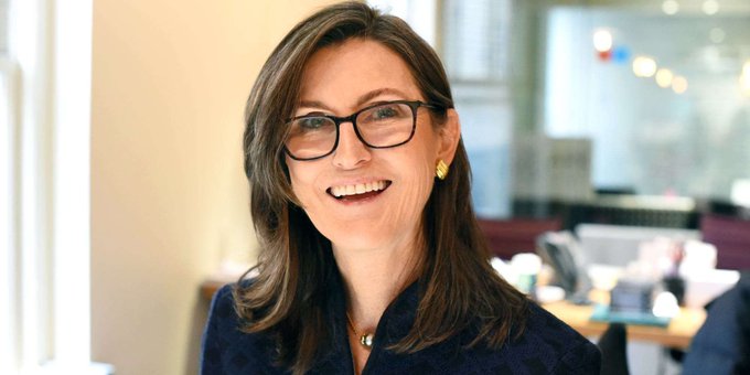 A smiling woman with glasses and shoulder-length brown hair, likely Cathie Wood, is pictured in what appears to be a bright office setting, aligning with the post about her Bitcoin investment advice for building generational wealth.