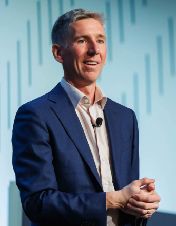 Bitwise CIO Matt Hougan speaks at an event, projecting confidence as he discusses bold predictions that blockchain transaction activity could be underestimated by 10x to 100x, driven by 24/7 tokenized stock trading and AI agents executing trades on behalf of users.