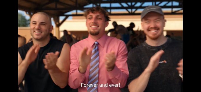 A screenshot from a video showing three men, with MrBeast in the center wearing a pink shirt and tie, clapping with the subtitle 'Forever and ever!'