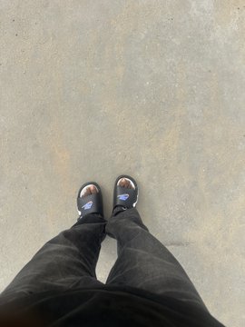 A person stands on a concrete surface wearing black platform sandals and dark pants, capturing a top-down view of their feet—a casual, on-the-go moment that complements the post's highlights of an active day of moving around, creating content, and engaging with multiple communities.