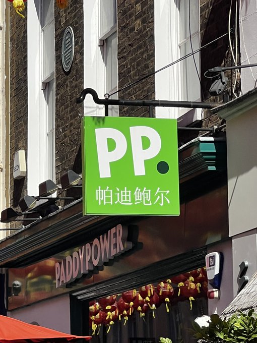 A bright green sign with "PP." and Chinese characters hangs above a Paddy Power shop. This is relevant to "Gm degens" as Paddy Power is a betting company, and "degens" is slang for degenerates, often referring to those who gamble.