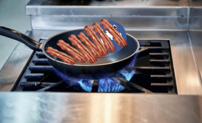Bacon strips sizzle in a frying pan over an open flame, humorously arranged to form the shape of the Facebook "f" logo, playfully tying into the "wrapping Litecoin in bacon" post.
