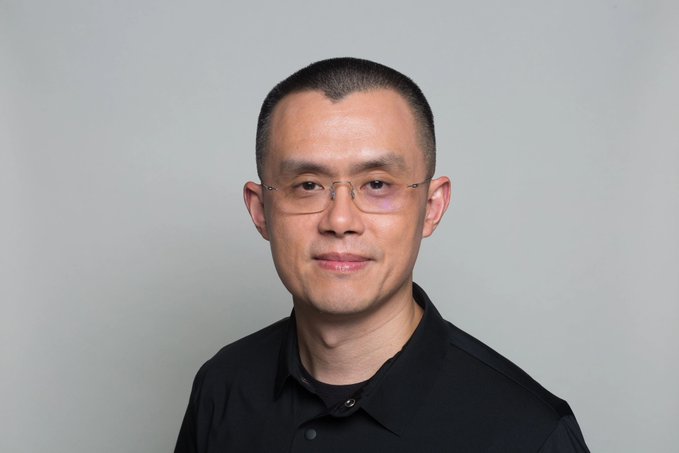 The image shows a man with short black hair wearing rimless glasses and a black collared shirt, posing against a plain light gray background. He has East Asian features and is looking directly at the camera with a subtle smile, which matches the post's humor as he is indeed not CZ (Changpeng Zhao), the Binance founder.