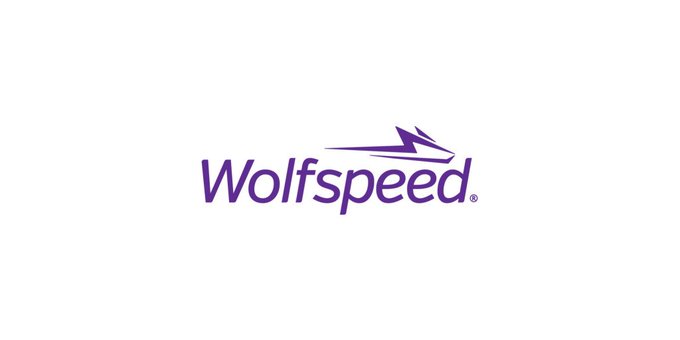 The Wolfspeed logo features the company name in purple text accompanied by a stylized wolf head graphic, representing the semiconductor company ($WOLF) that received up to $1.5 billion in conditional funding from the U.S. Department of War to support domestic silicon carbide production.