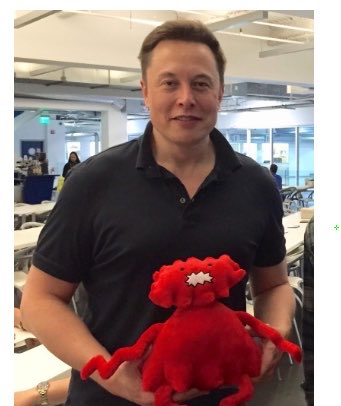 A man holding a red stuffed animal in what appears to be a tech office setting.