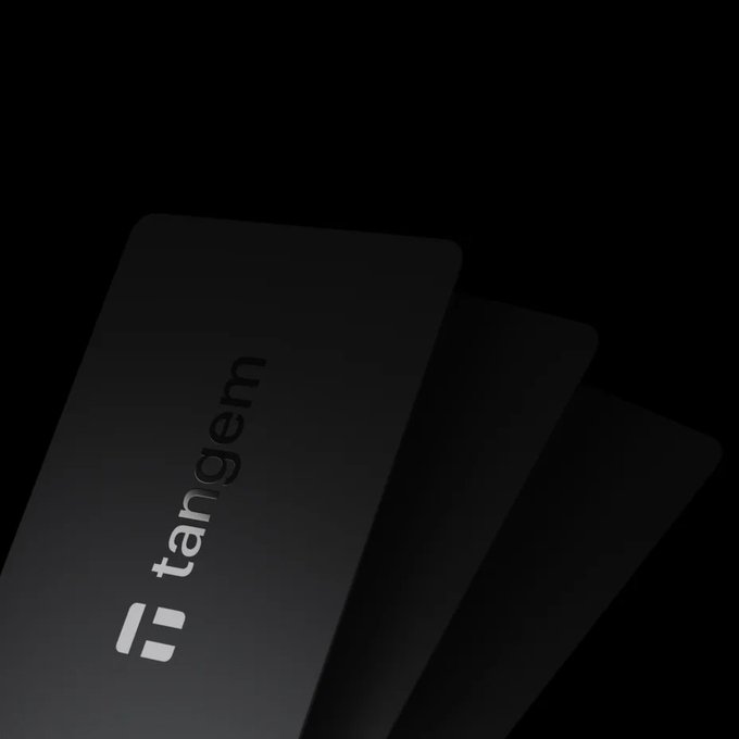 Three dark gray cards are fanned out against a black background, with the top card displaying the word "tangem" and a stylized logo.