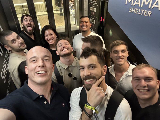 A group of men pose together for a selfie inside an elevator, with 'MAMA SHELTER' visible on the wall behind them.