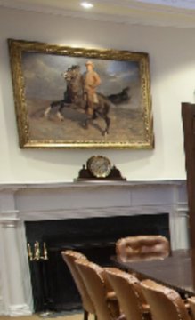 A formal room features a large painting of figures on horseback mounted above a white marble fireplace with a decorative clock, where people are seated around a polished table—setting the scene for a meeting between Brad and Trump in the Roosevelt Room.