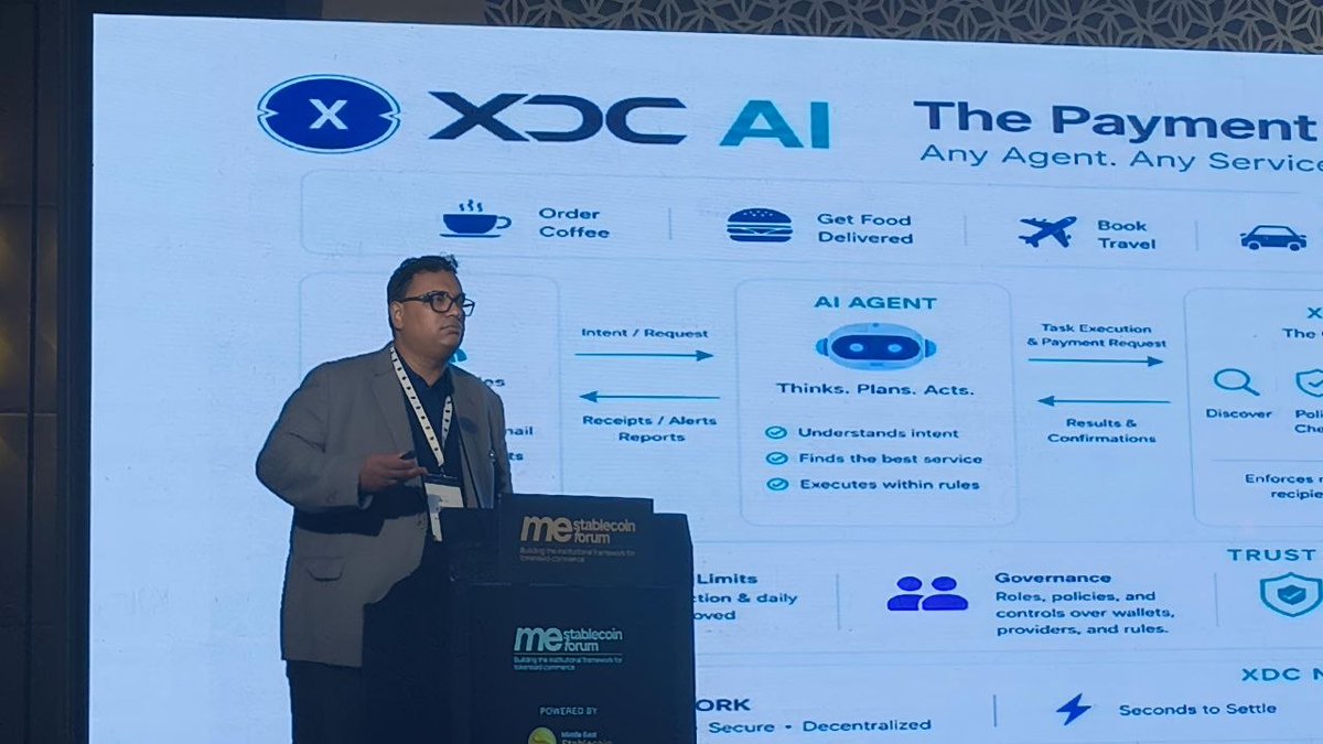 A man in glasses and a lanyard presents at the "me stablecoin forum" podium, standing in front of a large screen displaying the "XDC AI" logo and a slide titled "The Payment [layer]" with the tagline "Any Agent. Any Service." The slide illustrates how AI agents handle tasks like ordering coffee, getting food delivered, booking travel, and ride services, showing processes including "Intent/Request," "Task Execution & Payment Request," and "Receipts/Alerts Reports," while highlighting features such as "Thinks. Plans. Acts.," "Understands intent," "Governance," "Trust," and "XDC N[etwork]" with "Seconds to Settle."