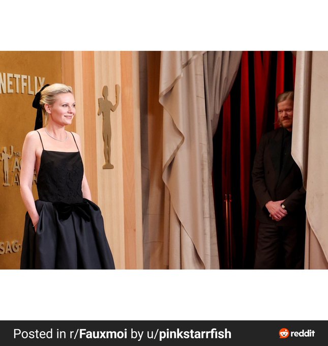 The image features two individuals, one standing behind the other, with the person in front wearing a black dress and the person behind them dressed in a suit. The background of the photo shows curtains and a sign that reads "PINKSTARFISH".