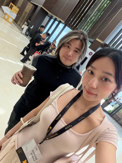 Two people pose for a selfie at what appears to be a tech event, with one holding a coffee cup and the other wearing lanyards displaying "ZCCX" and "CONNEXOR" badges. The image caption "Moon and Odysseus" suggests a playful reference to their names or personas, fitting the space/tech theme of the conference lanyards.