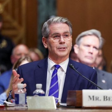 A man in a dark suit and purple striped tie speaks into a microphone at a Senate hearing, with a nameplate reading "MR. BE..." visible in front of him. The image illustrates the post's theme of measured policy dialogue around cryptocurrency regulation in a formal congressional setting.