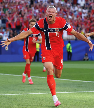 A soccer player in a red jersey with the number 4 celebrates with arms outstretched on the pitch during a match.
