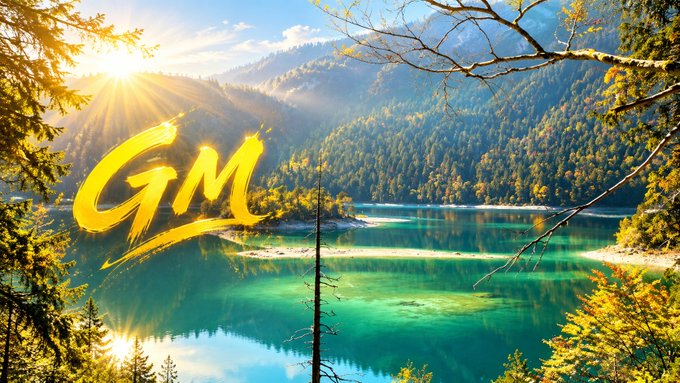 A scenic landscape showing a turquoise lake surrounded by forested mountains with sunlight breaking through trees, overlaid with stylized golden 'GM' text in the center.