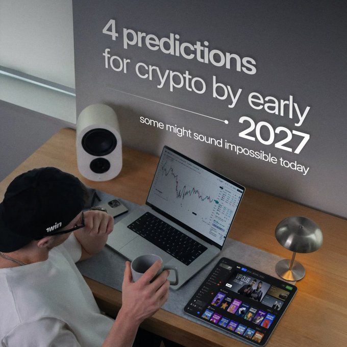 A person wearing a black cap works at a desk with a laptop displaying a stock chart and a tablet, with text overlay reading '4 predictions for crypto by early 2027' and 'some might sound impossible today'.