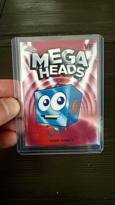 A hand holds up a "Rare Robot" Mega Heads card graded VF (Very Fine) by Card Chatronic, featuring a blue cartoon box-shaped robot character with big eyes and antennae against a red and white background. The post relates to the image by asking the VeeFriends community to help determine the value of this specific Rare Robot collectible card.