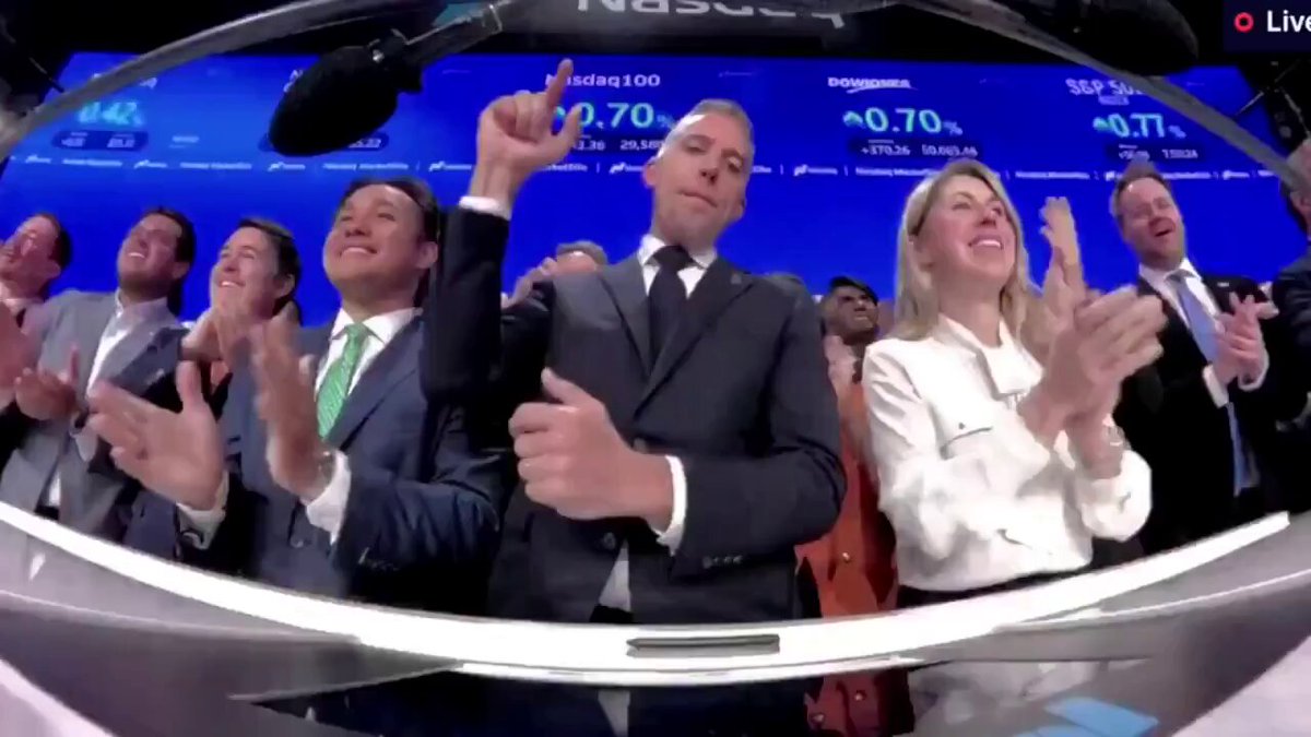 The image shows a group of people standing around, with some of them clapping their hands together. The scene appears to be taking place at an event or gathering where they are celebrating something related to Bitcoin. One person is holding up his hand, possibly making a gesture or giving a thumbs-up sign. The post about the Bitcoin Fund raises questions and concerns about the fund's purpose and how it works. It seems that the group of people in the image might be discussing these topics or reacting to the information presented in the post.