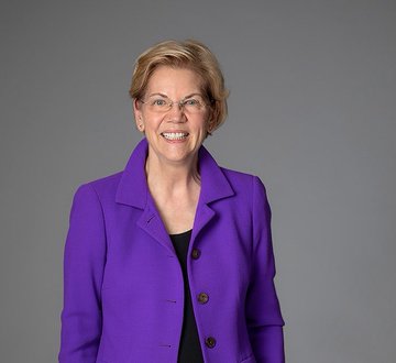 urny, a woman with blonde hair and glasses, smiles warmly against a gray background.