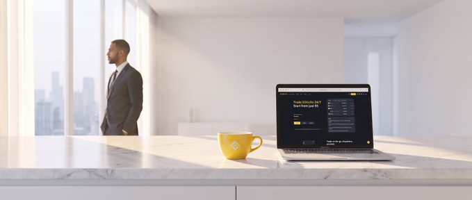 A man in a suit gazes out a large window at a cityscape while a laptop on a marble counter displays a website with a yellow coffee mug beside it.