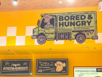 A wall mural for 'Bored & Hungry,' a plant-based restaurant in California, featuring a cartoon pig in a food truck and the tagline 'Bored of eating the same ol' same ol'?'