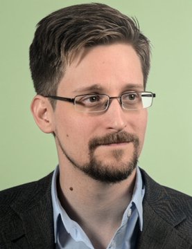 A man with short brown hair, glasses, a goatee, and a gray blazer over a blue shirt poses against a light green background, identified in the accompanying quote as Edward Snowden, who in 2022 likened gold to "Bitcoin that can't be sent over the internet."