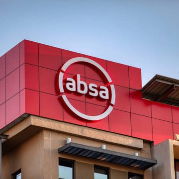 The image displays the exterior signage of an Absa bank branch, featuring the company's white "absa" logo prominently displayed within a circular emblem on a red facade. This image accompanies news that Absa, a major South African bank, has become the first African financial institution to offer institutional cryptocurrency custody services, supporting Bitcoin, Ethereum, XRPL assets, and USDC at launch.