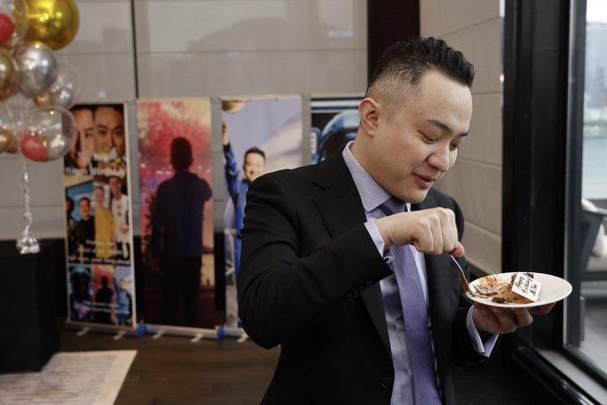 Justin Sun, founder of TRON, cuts into a birthday cake as he celebrates his 36th birthday at a private event. Behind him, posters showcase his career milestones, and gold and red balloons add to the festive atmosphere as he marks another year of his journey from vision to building a global blockchain ecosystem.