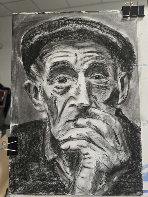 A detailed charcoal or pencil sketch portrait of an elderly man wearing a cap, with his hand resting thoughtfully against his face, displayed on an artist's easel.