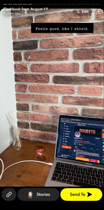 A Snapchat flashback from August 19 showing a brick wall background with a laptop displaying "DOOBITS" cryptocurrency interface, reed diffusers, and a small red figurine on a wooden desk, with the caption "Feelin good, like I should."