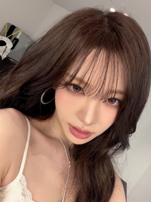 A young woman with long dark hair, delicate makeup, and a white lace top gazes softly at the camera in a close-up selfie. The image accompanies a post where the user laments the dull market, saying they have nothing to do but look at "Wife Liz" and asking web3 friends how they pass the time, suggesting the woman pictured is the K-pop idol Liz (리즈) of IVE, who the poster affectionately refers to as their "wife."