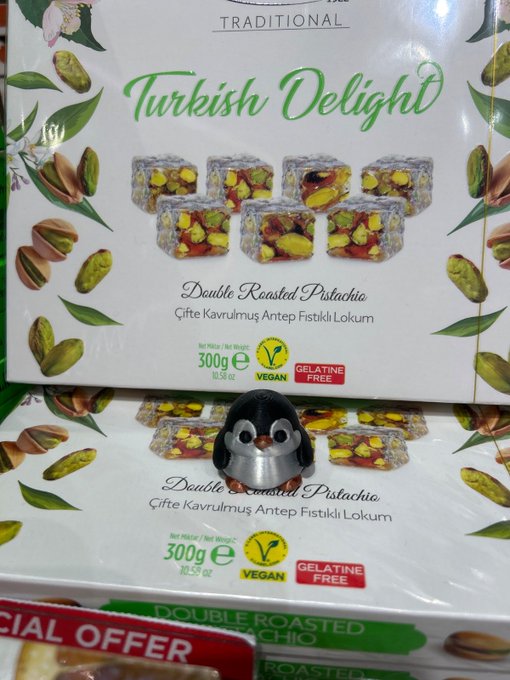 Boxes of Traditional Turkish Delight Double Roasted Pistachio lokum (300g, vegan, gelatine free) stacked on a store shelf, with a small penguin figurine sitting on the lower box.