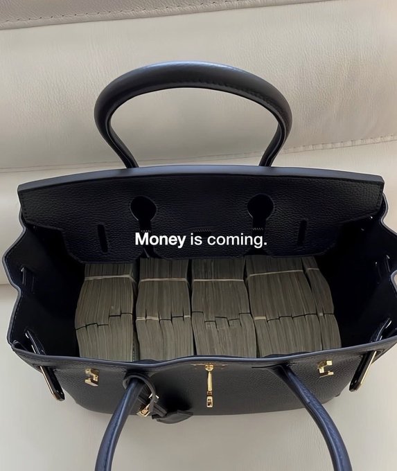 An open luxury black leather handbag filled with stacks of cash, overlaid with the text 'Money is coming.'