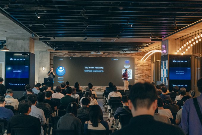 A large crowd fills the DreamPlus Gangnam venue for Ethene Labs' first Korea community event, where co-founder @GandalfTheBr0wn presents on a stage with screens displaying the slide "We're not replacing financial institutions" alongside the Ethene and DreamPlus logos.