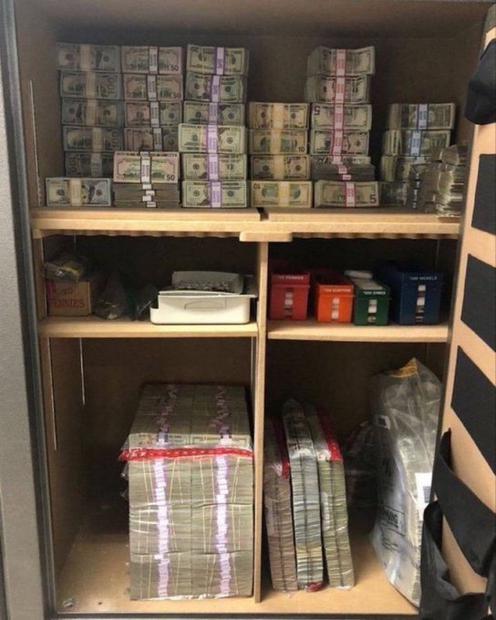 Photo of a safe or cabinet containing large stacks of bundled US dollar bills on shelves along with colored coin storage boxes and a box of pennies.