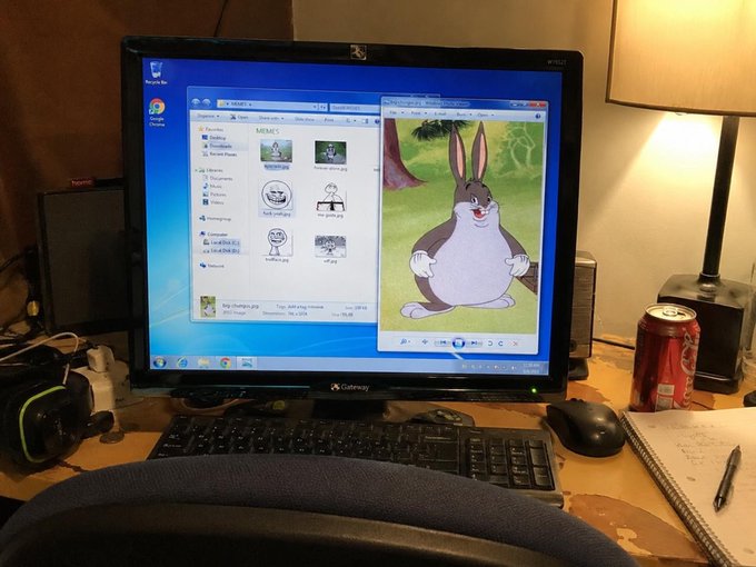 A computer monitor on a desk displays a Windows XP desktop showing a folder of meme images and a picture of Big Chungus, with a soda can and keyboard visible in the foreground.