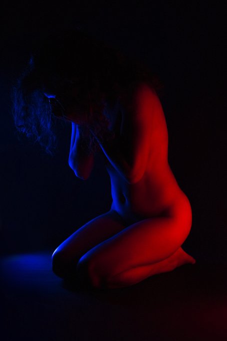 A nude figure kneels in shadow under dramatic blue and red lighting, evoking the post’s theme of “The healing power of tears”; no visible text or tickers.