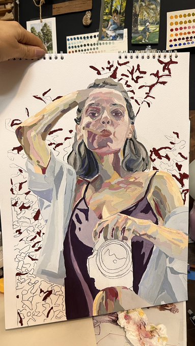 A painted portrait of a woman holding a coffee cup on a sketchpad, surrounded by dark floral motifs, shown in an artist's workspace with color swatches and reference photos in the background.