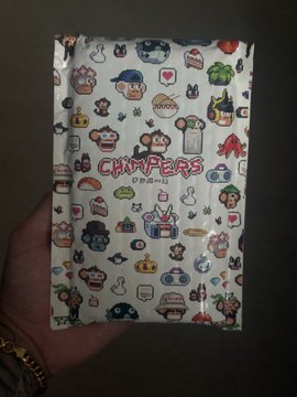 A hand holding a sealed package of 'Chimpers Originals' sticker pack, featuring various colorful character designs.