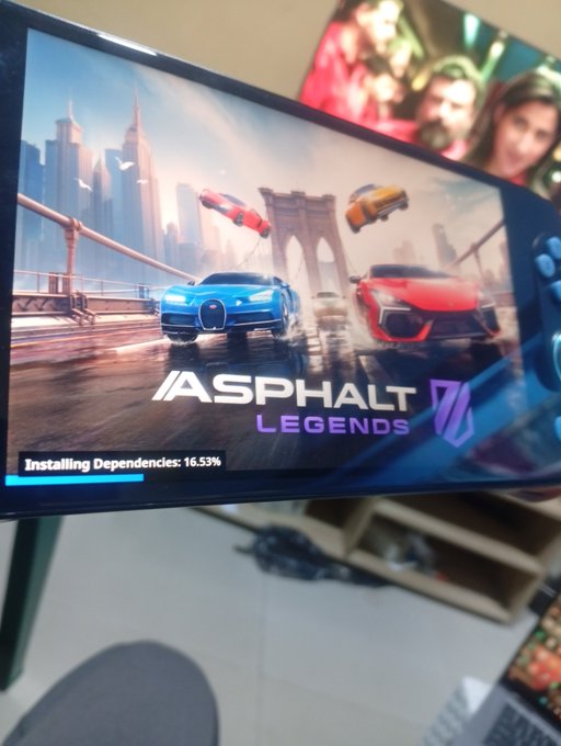 A TV screen displaying the loading screen for 'Asphalt Legends Unite' at 16.53% installing dependencies.
