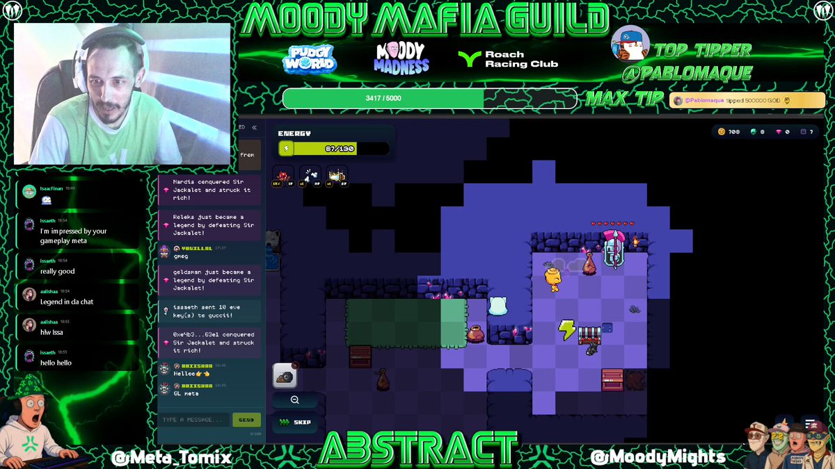 The image shows a man sitting in front of his computer screen playing a video game called "MOG" (Minecraft). The game has an interesting title, "MEGA jackpot on MOG @onchainheroes What a crazy week I’m having, I’ve hit all 3 jackpots!". The man is wearing headphones and appears to be enjoying the game.