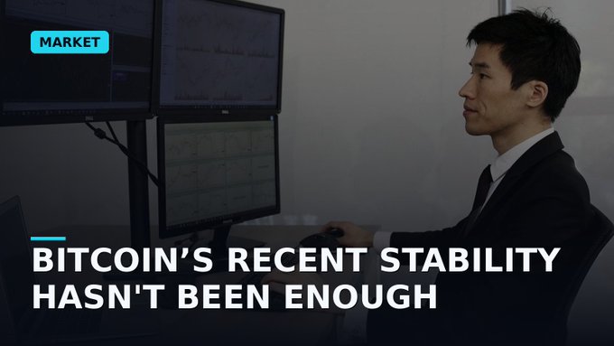 A news graphic with the 'MARKET' tag showing a man in a suit looking at financial charts on dual monitors, with the headline 'BITCOIN'S RECENT STABILITY HASN'T BEEN ENOUGH'.