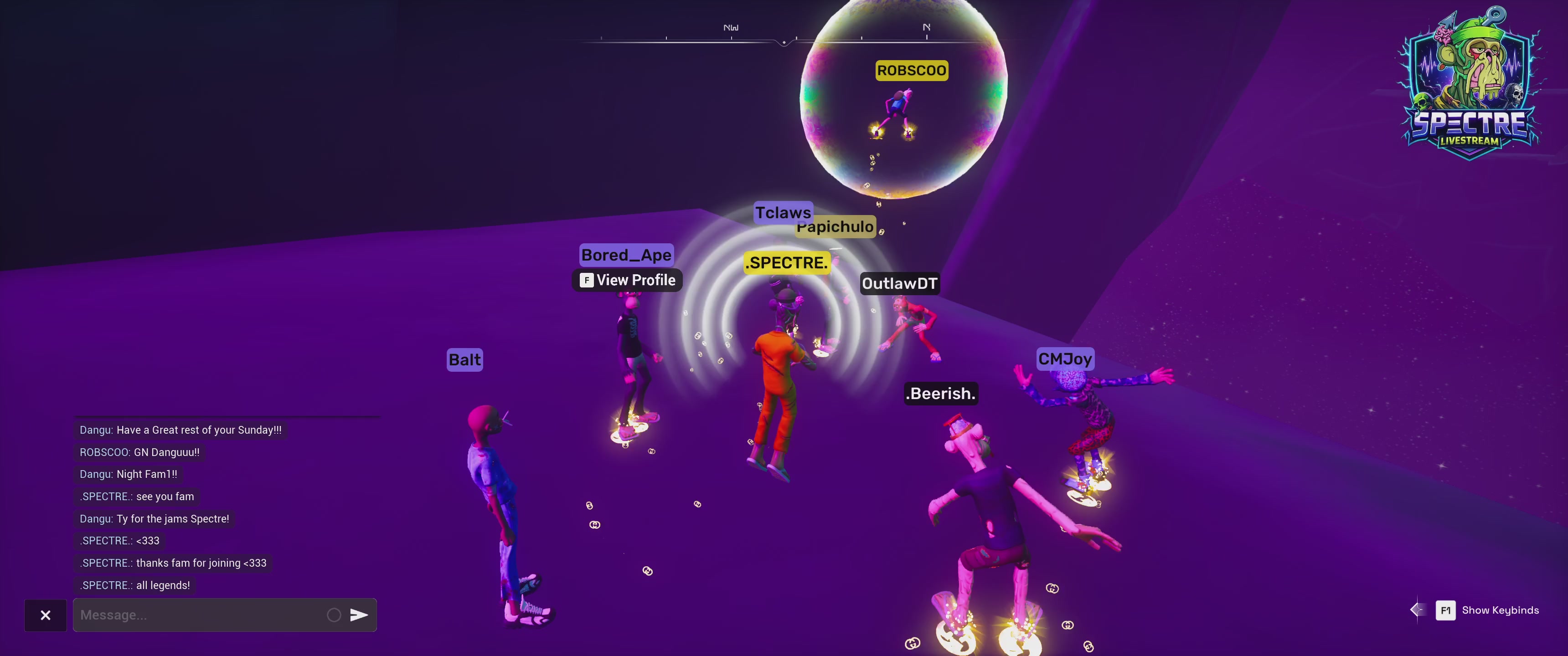 The image shows a group of people standing around each other, possibly engaged in conversation or preparing for an event. The main focus is on two individuals who are wearing orange jumpsuits and holding a large object that appears to be a giant speaker. They seem to be discussing something related to the speaker or its purpose. In addition to these two individuals, there are several others present in the scene, some of whom may also be involved with the speaker or the event. The image does not provide any specific information about the event itself, but it seems like a social gathering or an outdoor party where people have gathered around the speaker for discussion and interaction.