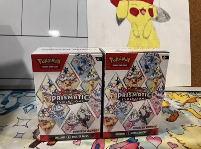 Two Pokémon Trading Card Game "Prismatic Evolutions" Booster Bundle boxes (6+) sit side by side on a Pokémon-themed surface, each containing 6 booster packs, with a drawing of Pikachu visible in the background. The post references opening preclaims for these bundles in exchange for a PKC stamped cosmo holo, suggesting a trade opportunity for the collector items shown.