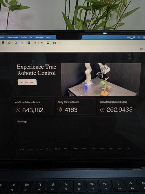 A laptop displays the PrismaX dashboard showing "Experience True Robotic Control" with 843,182 All-Time Prisma Points, 4,163 Daily Prisma Points, and 262.9433 Data Hours Contributed, illustrating the user's frustration about accumulating high platform points but receiving no monetary compensation despite over a year of QA review work.