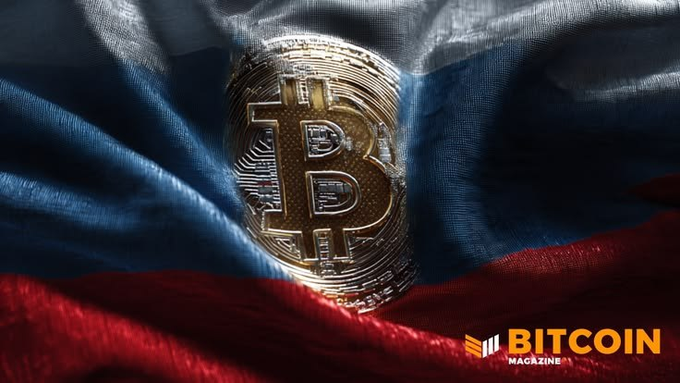 A golden Bitcoin coin resting on a Russian flag, with the 'BITCOIN MAGAZINE' logo in the bottom right corner.