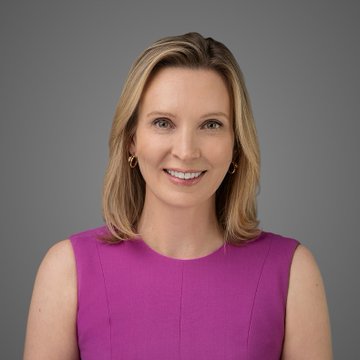A professional headshot of a woman with blonde hair wearing a bright pink sleeveless top, smiling against a gray background.

The image appears to be a headshot of a financial or political expert being featured alongside commentary about the CLARITY Act, suggesting she may be an analyst, lobbyist, or commentator providing insight on the legislation's potential passage.