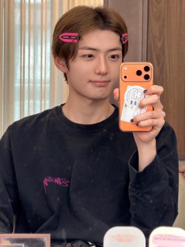 A young man with pink hair clips takes a mirror selfie using an orange phone, wearing a black long-sleeve shirt with "Pink Punk" printed on it. The hashtags suggest this is related to Alpha Drive One (ALD1), with the person identified as Sanghyeon, a member of the group.